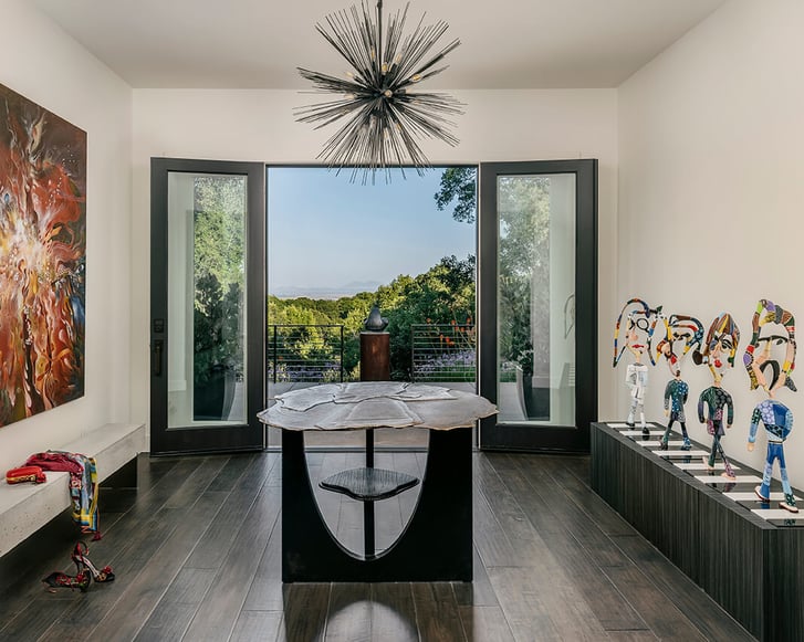 Modern entry with sculptural light fixture, art displays, and open doors to outdoor view by JS Design + Build in Napa, CA